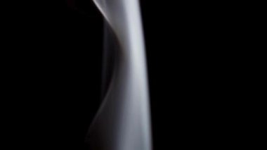 Beyaz dumanın karmaşık dokuları, yükselirken ve siyah bir arkaplana karşı zarafetle girdap oluştururken yakından çekilir..