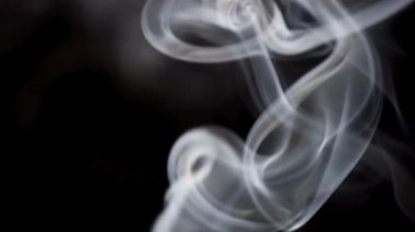 Karmaşık dokular ve kaotik hareketler gösteren, koyu siyah bir arkaplana doğru yükselirken, beyaz dumanın detaylı biçimde yakın plan görüntüsü..