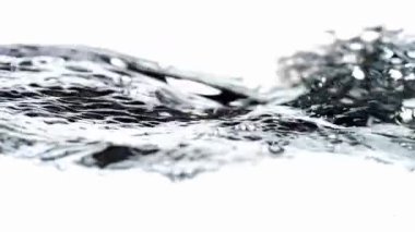 Kristal berrak su yüzeyinin yakın çekimi dalgalanmalar ve su kabarcıkları parlak beyaz bir arkaplan boyunca ilerlerken temiz ve ferahlatıcı bir stüdyo ortamında