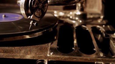 Antika bir gramofon iğnesinin nostaljik ve klasik bir müzik stüdyosunda dönen siyah bir plak çalarken detaylı bir yan görüntüsü.
