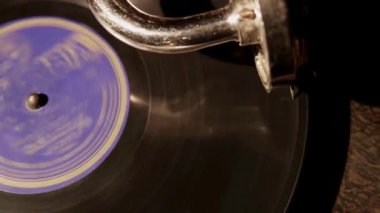 Yüksek açı, mavi etiketli vinil plağın yakın görüntüsü. İğne kolu müzik çalarken eski bir gramofonda dönüyor.