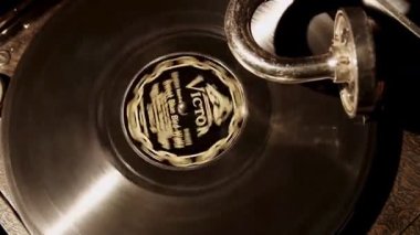 Kaliteli yakın çekim, antika bir gramofon plakçaların karanlık bir odada klasik etiketli siyah bir vinil disk döndürmesi.