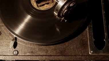Antik bir gramofoncunun geniş açılı sinematik görüntüsü, dönen vinil plaklı ve ton kollu karanlık seans sırasında yerleştirilmiş.