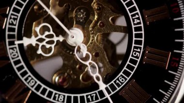 Mekanik iskelet saat mekanizmasının yüksek açılı makro görüntüsü beyaz süslemeli eller dönen altın dişlileri süpürüyor ve bronz iç saat bileşenleri hareket halinde