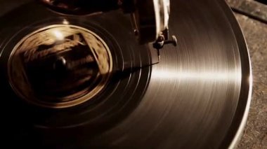 Klasik bir antika gramofon pikabının üzerinde düzgün dönen otantik vinil kayıt sıcak sinematik ışıklandırma ile nostaljik ses kaydı için kanallardan geçen iğneyi vurguluyor.