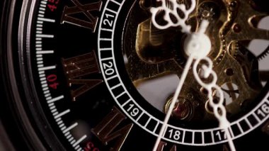 Zarif bir iskelet cep saatinin makro çekimi, Roma rakamlarıyla çalışan siyah bir kadranın arkasında çalışan karmaşık hareket eden dişlileri ve mekanik kaçışı gösteriyor.