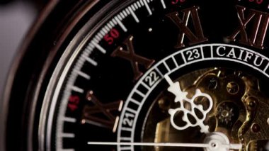 Lüks bir iskelet cep saatinin makro görüntüsü. Karmaşık beyaz eller, altın iç dişlilerin üzerinde hareket ediyor ve Roma rakamlarıyla siyah kadranlı.