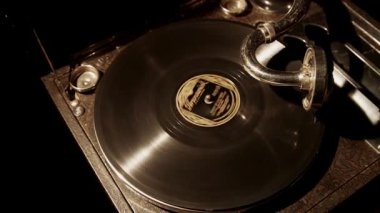 Dönen diskin detaylarını gösteren loş ışıklı bir ortamda dönen vinil plaklı klasik bir gramofonun üst görüntüsü