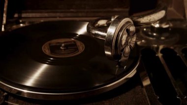 Loş ışıklı bir odada klasik mekanik parçaları ve dönen diski vurgulayan loş bir odada siyah plak çalan klasik bir gramofonun yan görüntüsü