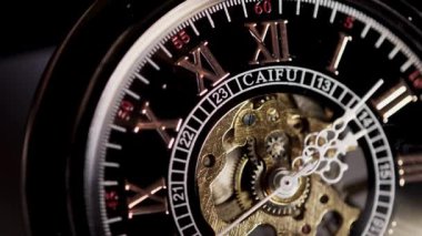 Klasik bir mekanik cep saatinin açılı perspektifi. İçi görünür bir iskelet. Altın dişliler ve beyaz ellerle siyah Roma rakamlı bir yüze karşı.