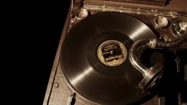 Klasik çalma cihazının detaylarını gösteren loş ışıklı bir ortamda dönen siyah bir vinil plakla klasik gramofonun yukarıdan aşağı görüntüsü