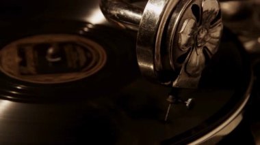 Kaliteli bir gramofon iğnesinin, loş bir odada, sıcak sepia tonlarıyla ve gölgeleriyle dönen siyah bir plak çalarkenki detaylı yakın çekimi.