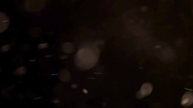 Havada süzülen toz parçacıkları ve yumuşak bokeh ışık lekelerinin karanlık bir atmosferik zemin üzerinde dans ederek arka plan efekti ya da arkaplan dokusu olarak kullanılması.