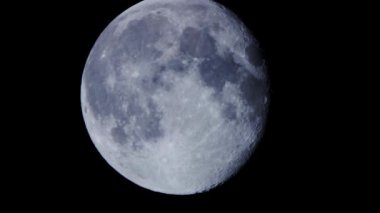 Parlayan dolunayın çok detaylı bir görüntüsü karanlık gece gökyüzünde yavaşça ilerlerken kraterleri ve ay yüzeyini ortaya çıkarıyor.