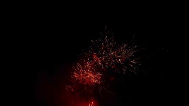 Güzel altın ve kırmızı havai fişekler, parlak ışık ve kıvılcımlarla dolu bir kutlamada karanlık bir gece gökyüzüne karşı patlıyor.