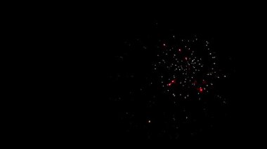 Küçük altın ve kırmızı havai fişekler gecenin karanlığında gökyüzünde çoklu parlak ışık kıvılcımlarıyla şenlik kutlamalarında patlıyor.