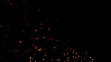 Altın ateş kıvılcımları ve parlak turuncu közler gece vakti şenlik ateşi ya da açık hava kutlaması sırasında karanlık bir arka plana doğru yükseliyor.