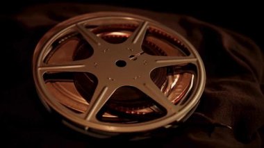 Klasik gümüş film makaraları ve metal kaplar yakın çekim sıcak sinematik düşük aydınlatma ortamı altında koyu bir kumaş üzerinde dinleniyor