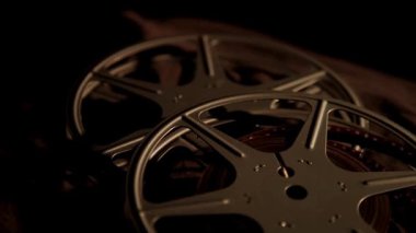 Birden fazla klasik film karanlık bir yüzeyde düz yatar ve eski film teknolojisinin detaylarını yavaş yavaş gösterir.