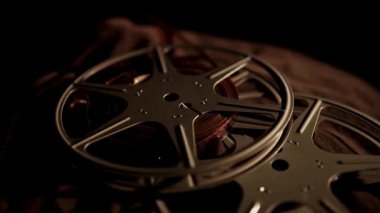 Birden fazla klasik film karanlık bir yüzeyde düz yatar ve eski film teknolojisinin detaylarını yavaş yavaş gösterir.