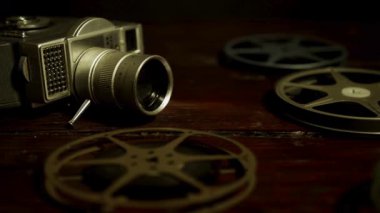 Klasik film kamerası ve eski filmler klasik odadaki loş karamsar ışığın altında, koyu ahşap masanın üzerinde uzanıyorlar.