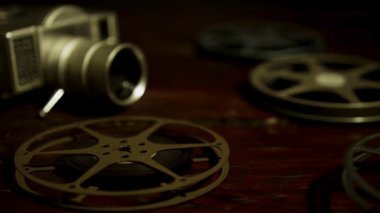 Antika film kamerası ve birkaç metal film makarası eski moda hissetmek için kasvetli, ahşap arka planda dinleniyor.