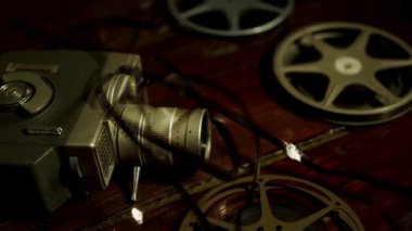 Klasik film kamerası ve eski filmler klasik odadaki loş karamsar ışığın altında, koyu ahşap masanın üzerinde uzanıyorlar.