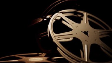 Yığılmış klasik metal film, mekanik dairesel şekilleri ve boş makaraları aydınlatan ılık kenar ışıklarıyla karanlık bir odada makaralar halinde.