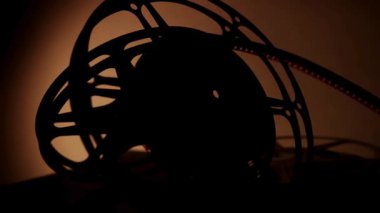 Klasik sinema filmi, masadaki siluetleri, klasik film estetiği ve dramatik gölgelerle sıcak stüdyo ışıklarında dinlendirir.