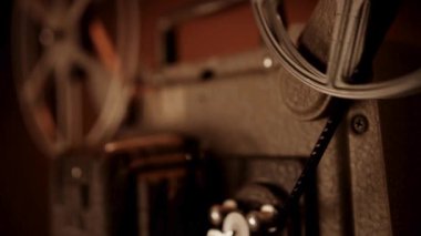 Dönen makaralı klasik film projektörü ve loş ışıklandırmalı film şeridi. Sinema nostaljisi için.