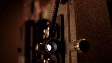 Hareket eden film şeridi ve lens yuvasından gelen yanıp sönen ışıkla çalışan klasik film projektörünün aşırı yakın çekimi.