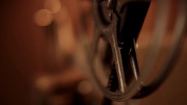 Ön planda dönen bir film makarası ile odak dışında sıcak atmosferik oda ışıklandırmasıyla bir bokeh etkisi yaratıyor.