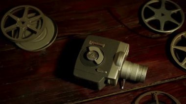 Kaliteli 8mm 'lik bir kamera ve koyu ahşap bir masada sıcak ortam aydınlatmalı birden fazla film makarası.