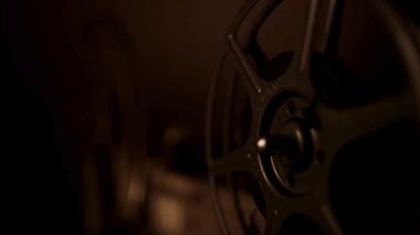 Eski bir klasik film gösterimi sırasında, film projektörü karanlık odada sıcak ışıkla dönüyor.