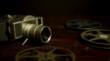 Klasik retro film kamerası ve metal makaralar profesyonel sinema tarihi ve eski okul film yapımı için koyu ahşap arka plana yerleştirilir.