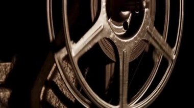 Karanlık odada, film projektörü mekanizmasında hızlı dönen klasik film makarası. Ilık ışıklandırma efektleri de var.