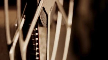 Ekstrem makro film şeridi sıcak sepimatik ışıklandırmayla klasik metal bir makarada hareket ediyor.