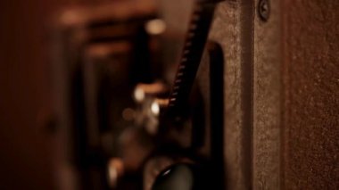 Klasik film projektörü, karanlık, sıcak, sepia odasındaki projeksiyon lensine kadar dönüyor ve dönüyor.