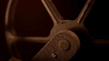 Karanlık bir odada film projeksiyonu sırasında dönen klasik bir film makarasının merkezini kapatın.