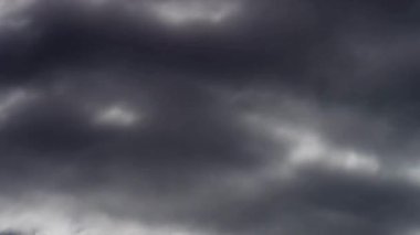 Değişen ışık ve atmosferik basınç ortamı ile hızlandırılmış bir geçiş sırasında derin mavi gökyüzünde hareket eden dramatik kara fırtına bulutları.