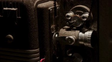 Eski bir film şeridinin gösterimi sırasında hareket eden klasik bir projektör merceği ve mekanik dişlerin ayrıntılı şekilde kapatılması