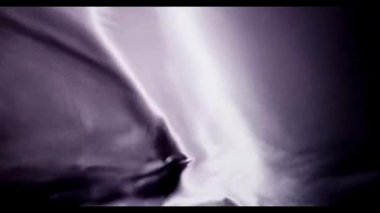 Pahalı video içeriği için zarif ve pürüzsüz bir arkaplan yaratmak için yumuşak ışık altında sallanan ve dalgalanan mor ipek kumaş.