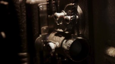 Klasik bir film gösterimi sırasında ışıklı ve mekanik parçaları hareket eden antik bir film projektörünün yan görüntüsü