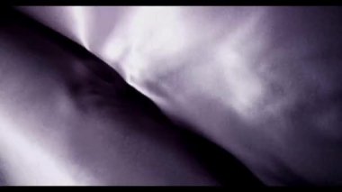 Derin menekşe ipekten kumaşlar yavaşça hareket ediyor ve aydınlık ve karanlıkta gölgeler yoluyla karmaşık dokular açığa vuruyor.