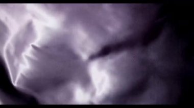 Işıldayan mor saten kumaş yavaş çekimde dalgalanır. Güzel röfleler ve derin gölgelerle lüks ve soyut bir tekstil arkaplanı yaratır.