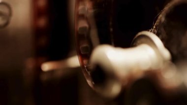 Klasik film projektörü çarkları 35 mm 'lik film makarasıyla dönüyor. Karanlık odadaki antika sinema ekipmanlarının yakın görüntüsü.