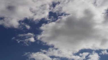 Aydınlık, güneşli bir günde, açık mavi gökyüzünde hareket eden tüylü beyaz bulutların güzel bir zaman atlaması.