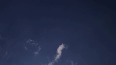 İnce beyaz bulutlar, berrak ve sakin bir yaz gününde engin bir mavi gökyüzü boyunca yavaşça sürükleniyor.