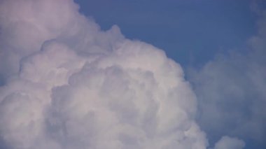 Parlak, beyaz, kabarık kümülüs bulutları, güneşli bir yaz gününde, açık mavi gökyüzüne karşı köpürüyor ve kayıyor taze bir esintiyle.
