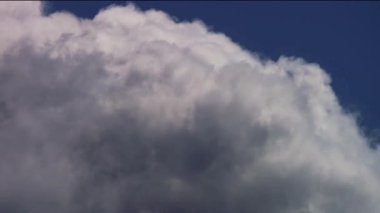 Beyaz kümülüs bulutu, parlak güneşli bir öğleden sonra, hafif rüzgar ve esintiyle canlı mavi gökyüzüne doğru genişliyor.